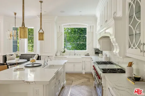 a kitchen with a stove a sink a center island and windows