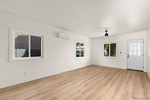 a kitchen with a sink dishwasher and white cabinets with wooden floor