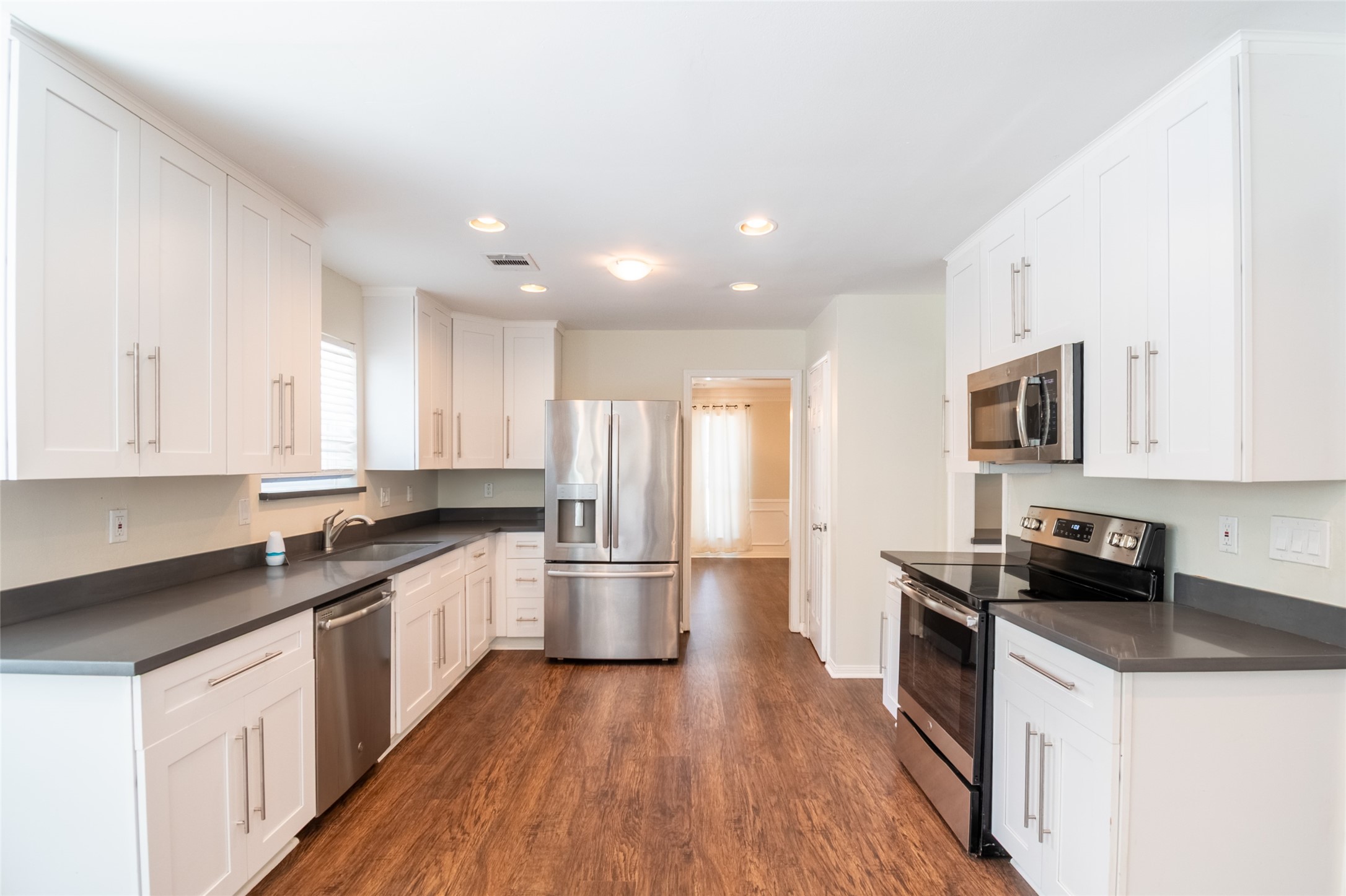 5607 Court Of York Houston, TX 77069 - Photo 16 of 45 a kitchen with stainless steel appliances a sink dishwasher a stove top oven a refrigerator with wooden floors and white cabinets