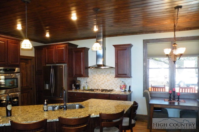 1459 Pine Ridge Road Beech Mountain, NC 28604 - Photo 13 of 25 a kitchen with granite countertop kitchen island stainless steel appliances a dining table and chairs