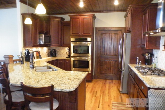 1459 Pine Ridge Road Beech Mountain, NC 28604 - Photo 19 of 25 a kitchen with granite countertop kitchen island stainless steel appliances a sink stove and refrigerator
