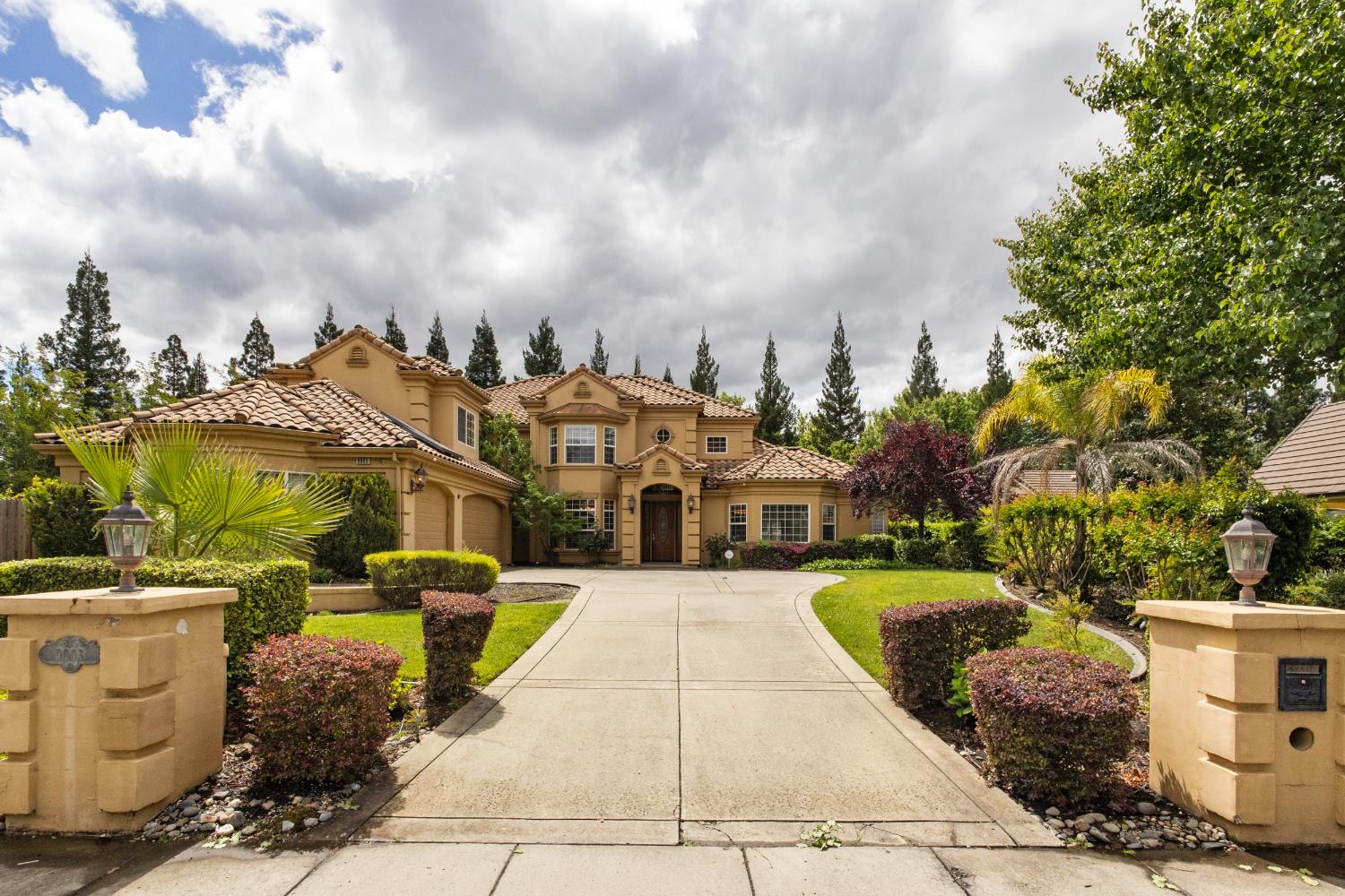 9003 Cedar Ridge Drive Granite Bay, CA 95746 - Photo 5 of 65 a view of a white house with a fountain plants and large trees