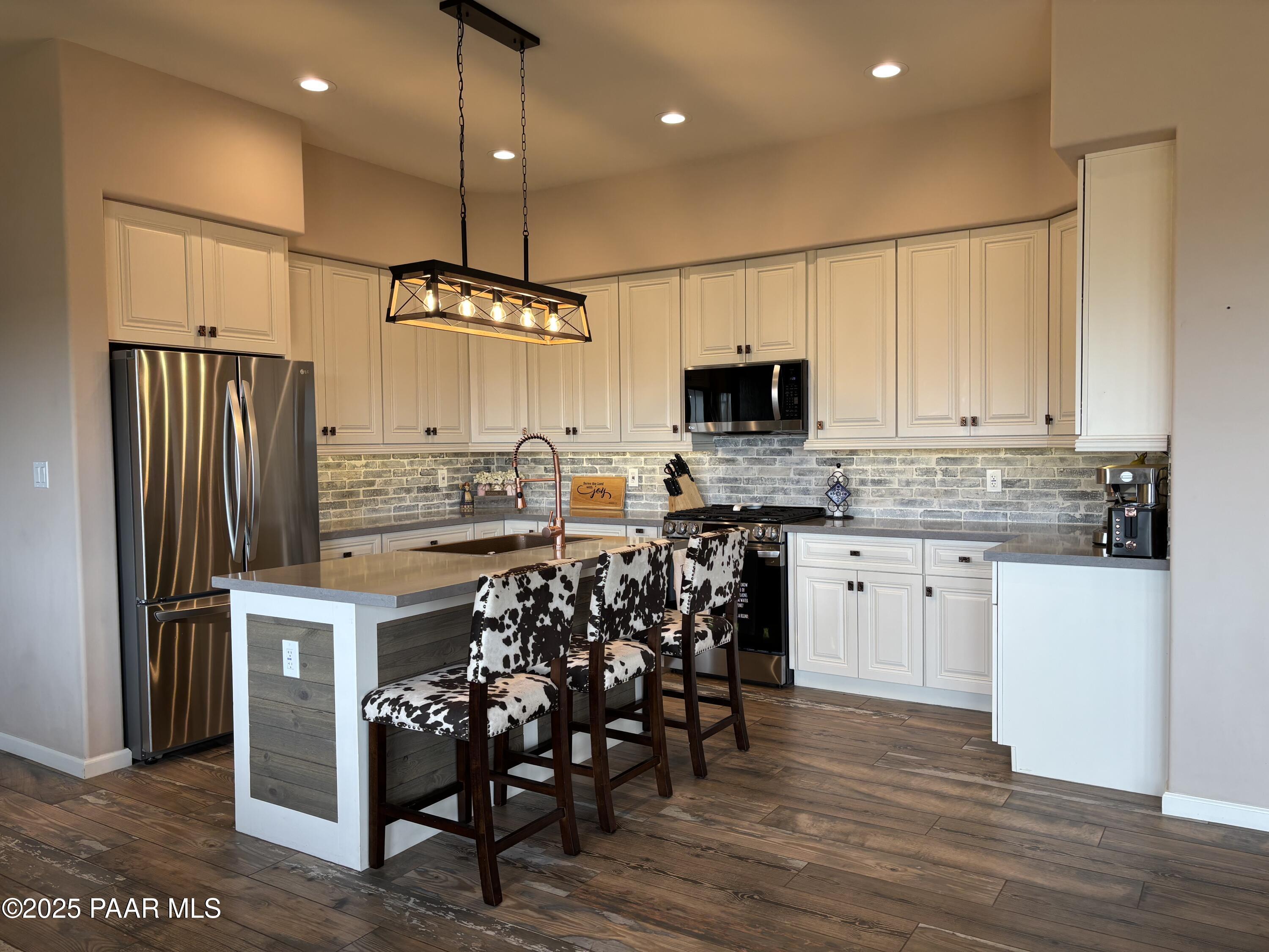 14994 North Hope Rose Road Prescott, AZ 86305 - Photo 4 of 33 a kitchen with stainless steel appliances granite countertop a refrigerator a stove a microwave oven a sink with island and chairs with wooden floor
