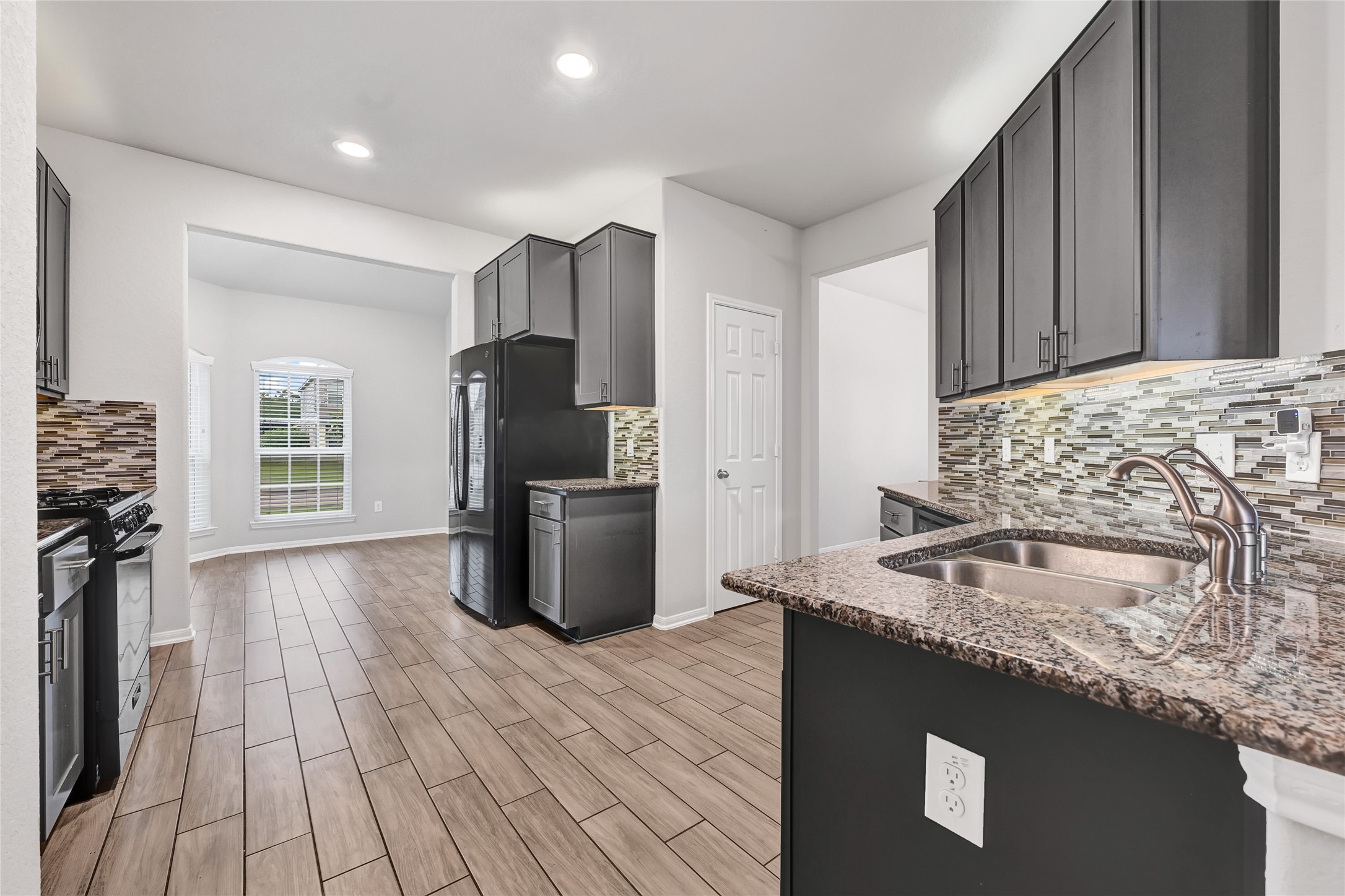 11346 Cascading Stream Way Houston, TX 77044 - Photo 9 of 24 a kitchen with granite countertop a sink stove refrigerator and cabinets