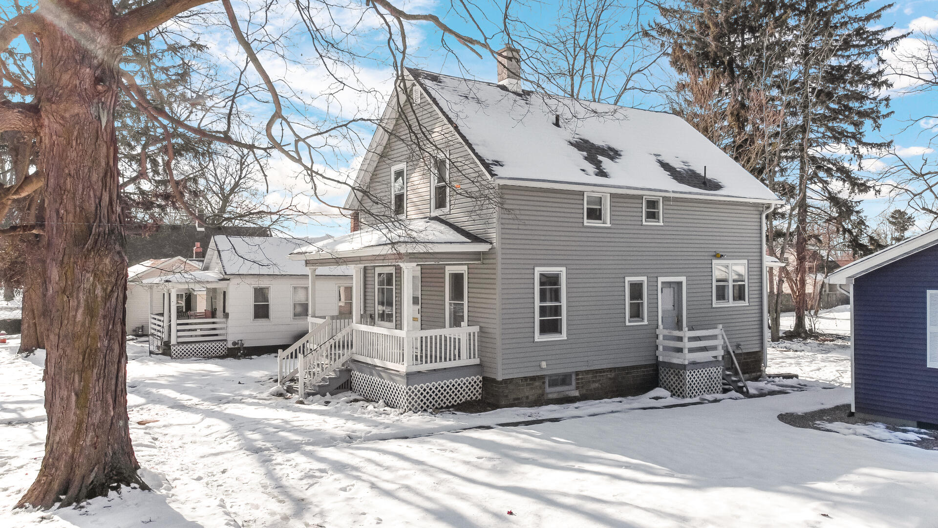 a view of a white house with a large tree in front of it