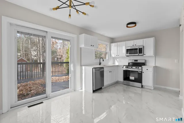 a kitchen with a refrigerator a stove top oven a sink and a large window