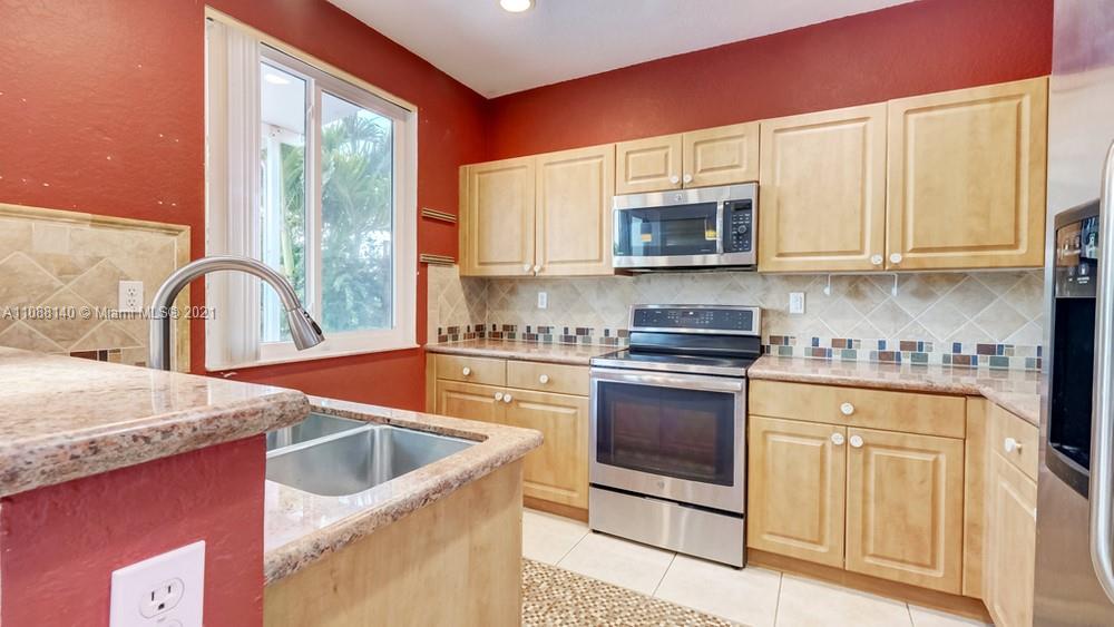 1311 Southeast 20th Road, Unit 1311 Homestead, FL 33035 - Photo 14 of 40 a kitchen with stainless steel appliances granite countertop a stove a sink and a microwave