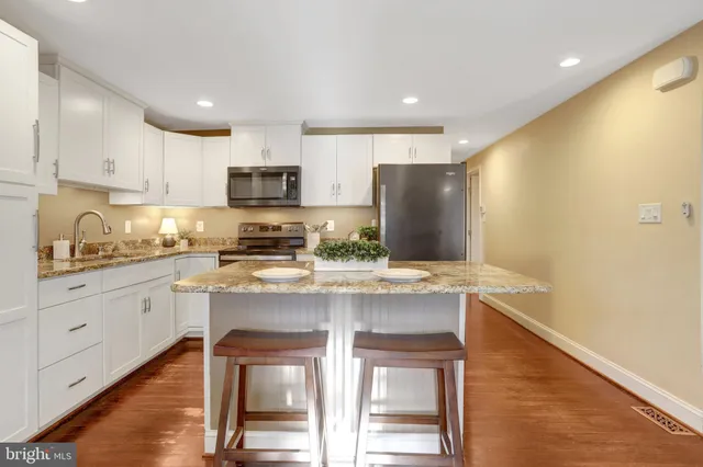 a kitchen with stainless steel appliances granite countertop a stove a sink a refrigerator and white cabinets