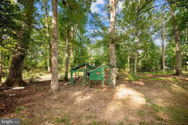 a view of a house with large trees and wooden fence