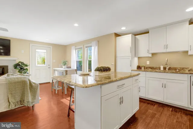 a open kitchen with white cabinets appliances and wooden floor