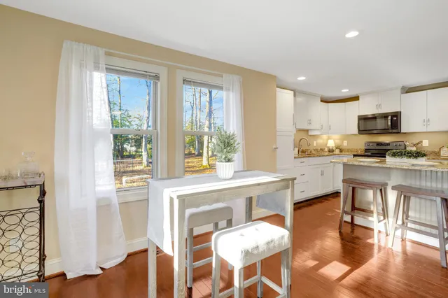 a kitchen with stainless steel appliances granite countertop a stove top oven a sink dishwasher and a refrigerator with wooden floor