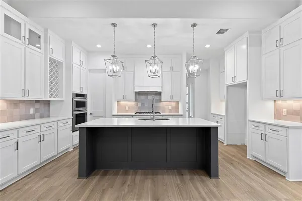 a kitchen with kitchen island granite countertop a sink cabinets and wooden floor