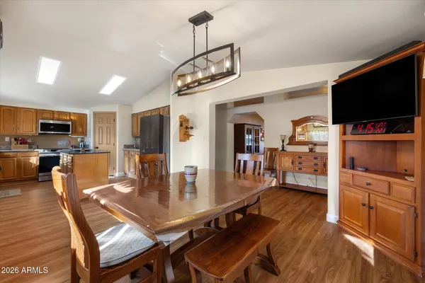 a dining room with wooden floor a chandelier a wooden table and chairs