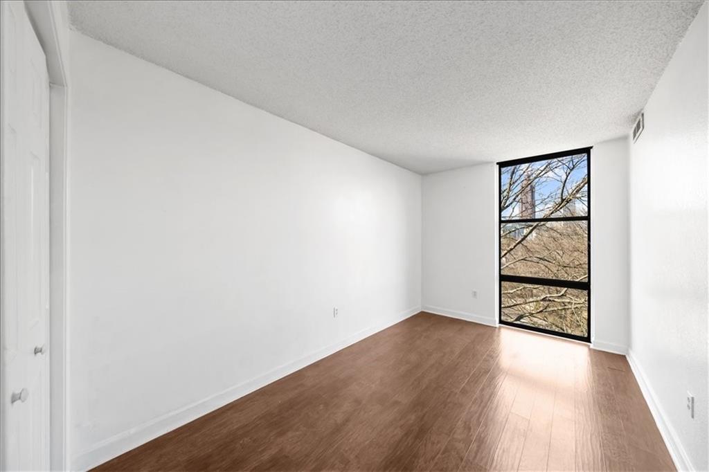 375 Ralph McGill Boulevard Northeast, Unit 407 Atlanta, GA 30312 - Photo 11 of 22 an empty room with wooden floor closet and windows