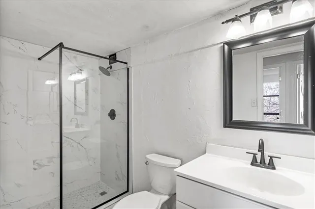 a bathroom with a shower a sink a toilet and mirror