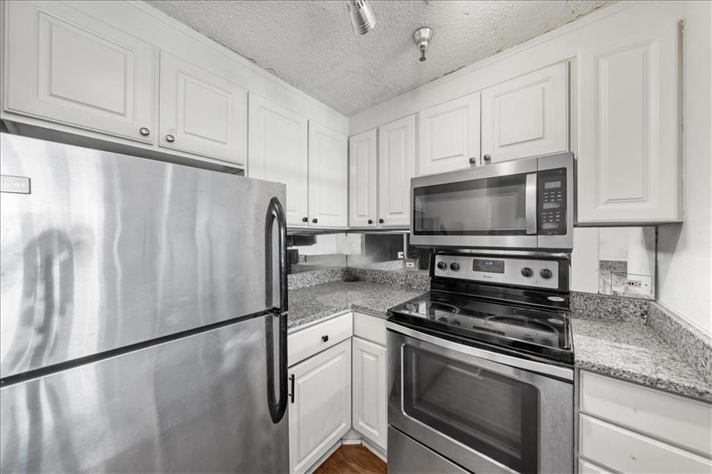375 Ralph McGill Boulevard Northeast, Unit 407 Atlanta, GA 30312 - Photo 2 of 22 a kitchen with granite countertop a refrigerator stove and white cabinets