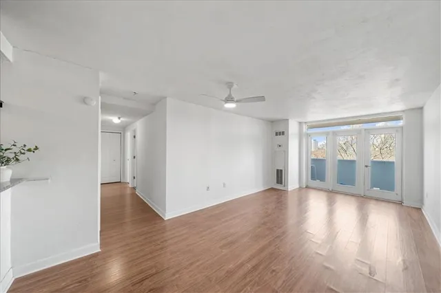 a view of an empty room with wooden floor and a window