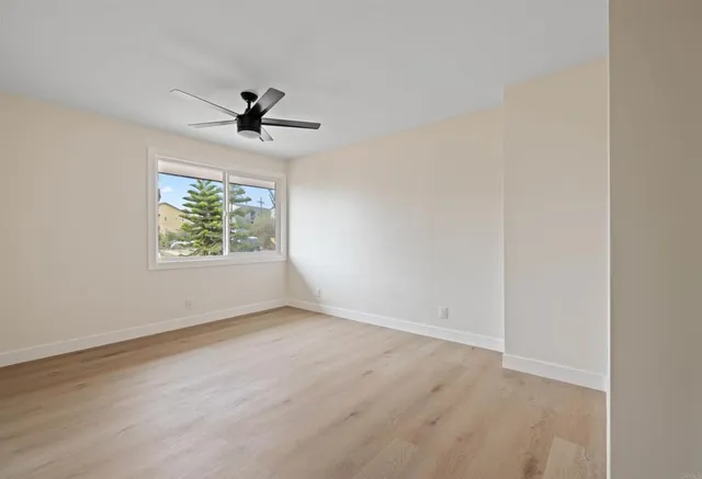 an empty room with a window and a ceiling fan