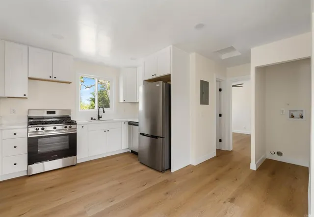 a kitchen with a refrigerator stove and wooden floor