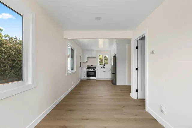 a view of a hallway with wooden floor and a kitchen