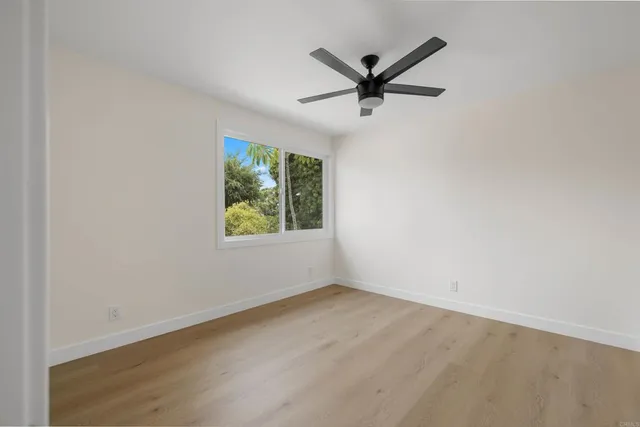 an empty room with window and ceiling fan