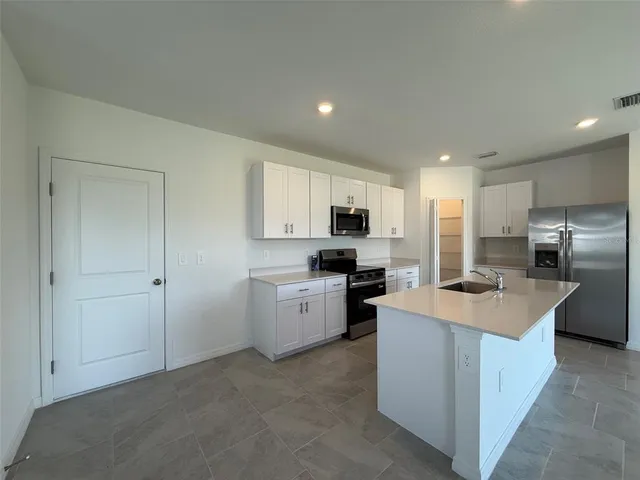 a kitchen that has a lot of white cabinets and stainless steel appliances