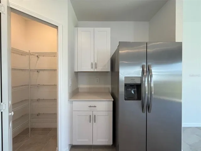 a kitchen with a refrigerator and white cabinets