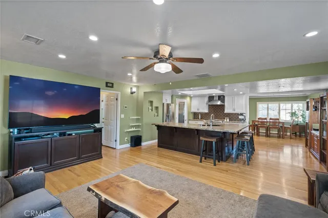 a kitchen with stainless steel appliances kitchen island granite countertop a table chairs and wooden floor