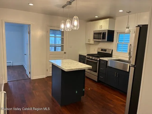 a kitchen with stainless steel appliances a sink a stove a refrigerator cabinets and wooden floor