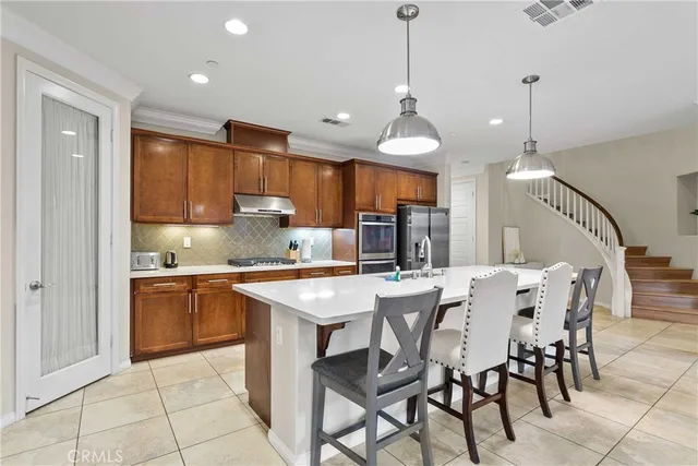 a kitchen with stainless steel appliances kitchen island granite countertop a sink a stove a dining table and chairs