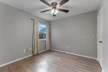 an empty room with windows and ceiling fan