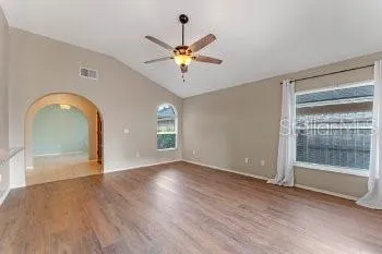 a view of an empty room with window and wooden floor