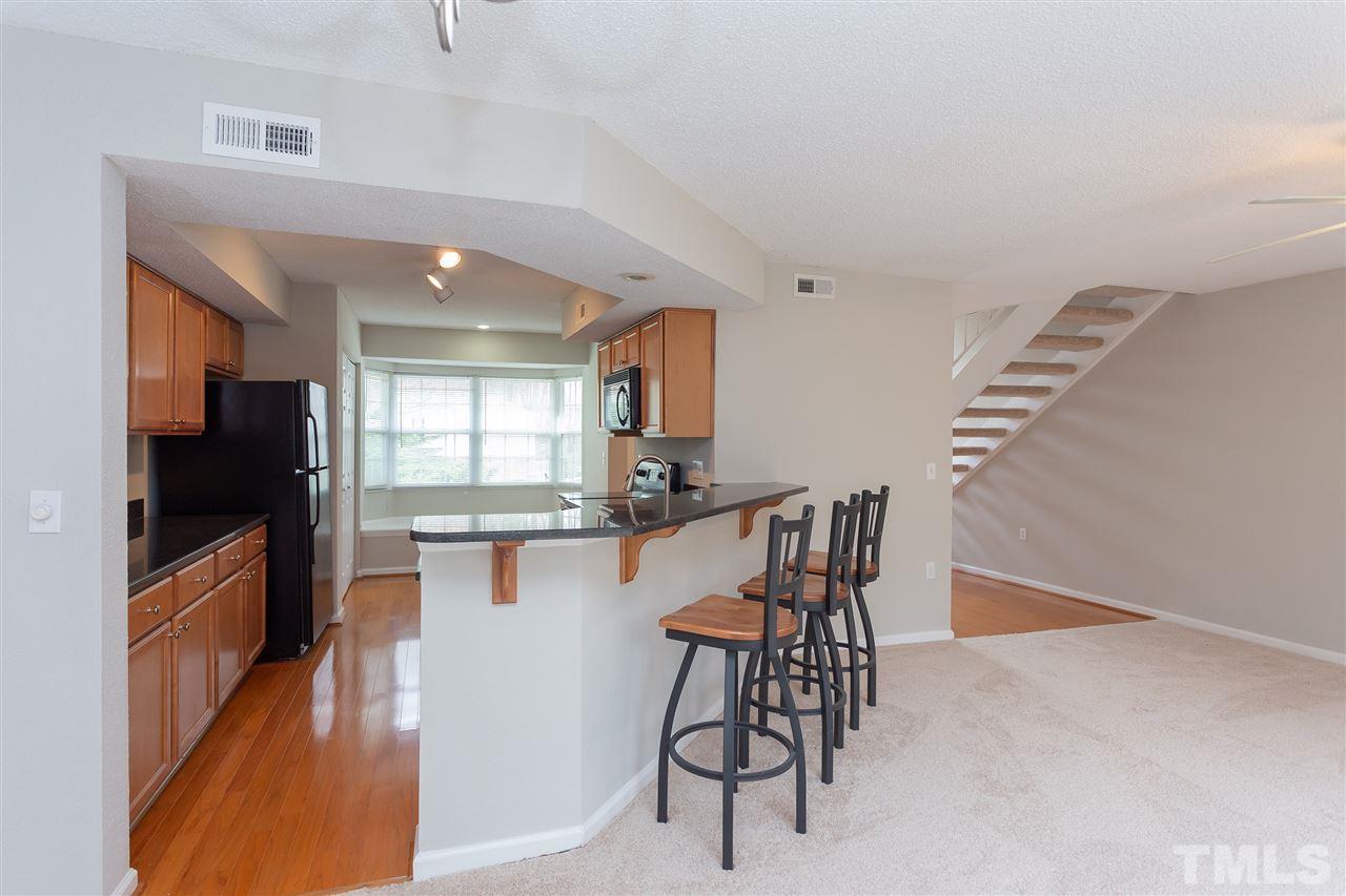 7812 Falcon Rest Circle Raleigh, NC 27615 - Photo 10 of 26 a kitchen with stainless steel appliances kitchen island granite countertop a refrigerator a stove a microwave oven a sink with island and chairs