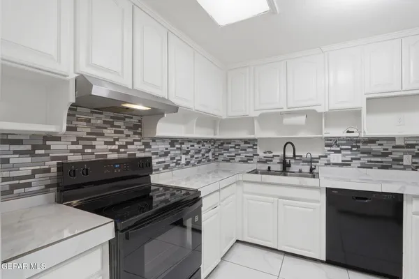 a kitchen with white cabinets and appliances