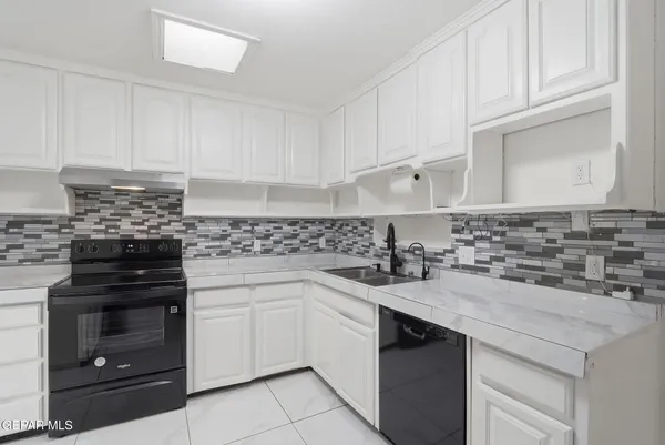 a kitchen with granite countertop white cabinets and stainless steel appliances