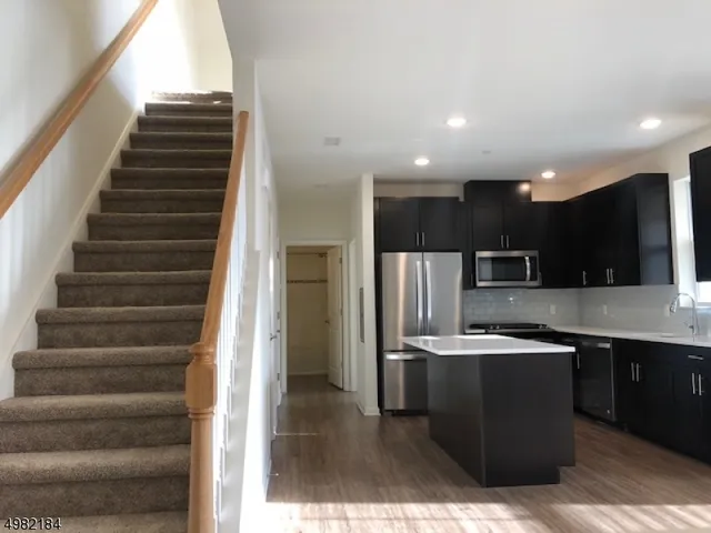a kitchen with stainless steel appliances kitchen island granite countertop a refrigerator and a sink