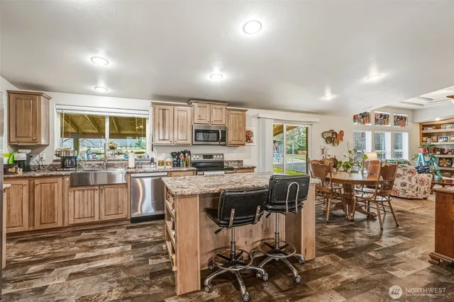 a kitchen with stainless steel appliances granite countertop a stove top oven a sink a dining table and chairs