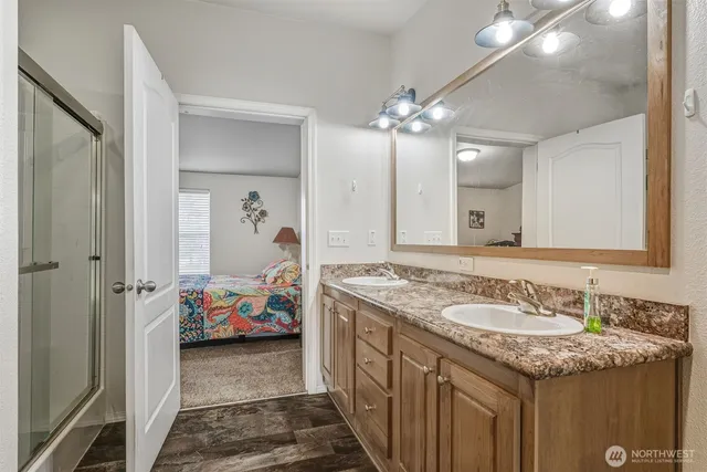 a en suite bathroom with a granite countertop double vanity sink and a mirror