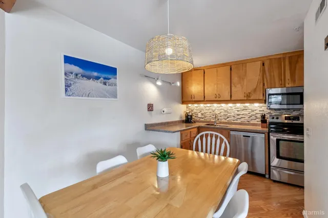 a kitchen with stainless steel appliances granite countertop a sink a stove a refrigerator cabinets and a dining table