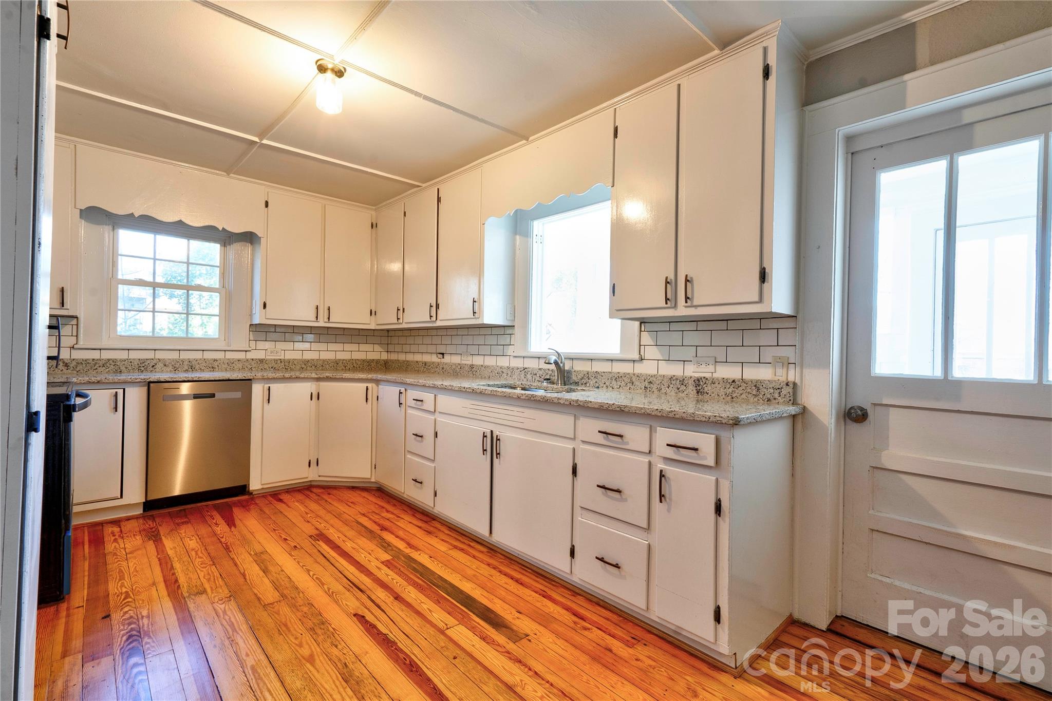 171 Center Street Spindale, NC 28160 - Photo 33 of 34 a kitchen with granite countertop wooden floors and white cabinets