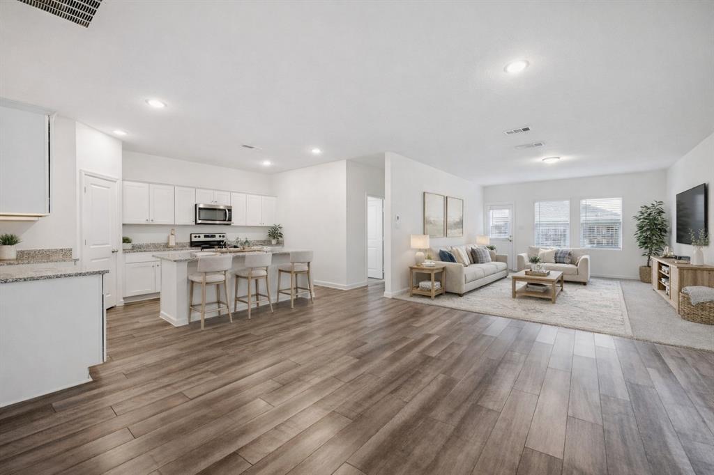 a living room with furniture and kitchen view with wooden floor