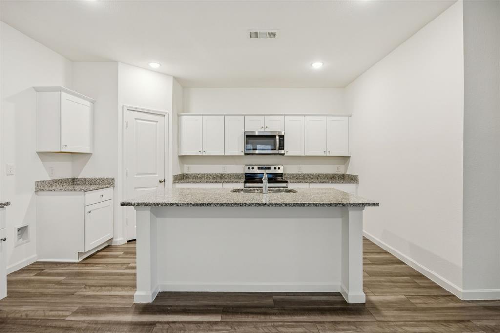 1902 Marquette Road Princeton, TX 75407 - Photo 5 of 30 a kitchen with stainless steel appliances granite countertop a sink stove a refrigerator and white cabinets with wooden floor