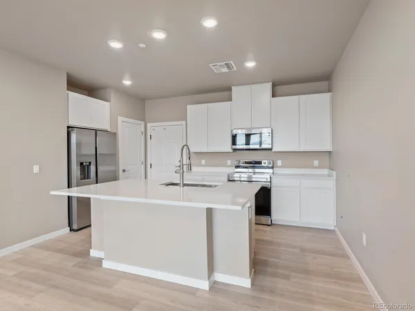 a kitchen with white cabinets and stainless steel appliances