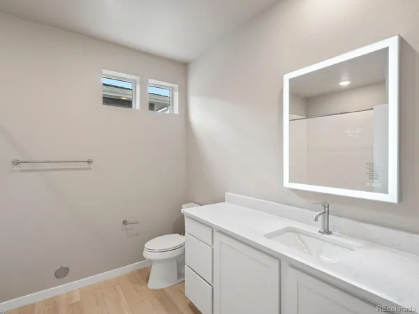 a bathroom with a granite countertop toilet a sink and a mirror