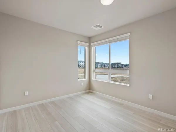 an empty room with wooden floor and windows