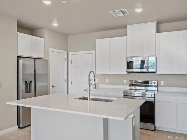 a kitchen with stainless steel appliances a sink a stove a microwave a refrigerator and cabinets