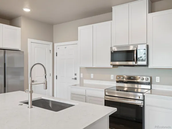 a kitchen with stainless steel appliances granite countertop a sink a stove and a refrigerator