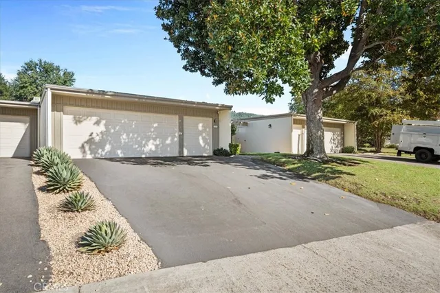 a view of a white house with a big yard and large trees