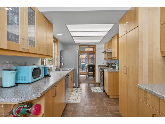 a kitchen with stainless steel appliances granite countertop a sink window and cabinets