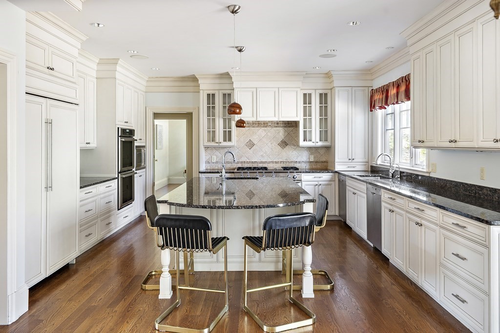 17 Kesseler Way Newton, MA 02467 - Photo 14 of 33 a kitchen with stainless steel appliances kitchen island granite countertop a refrigerator a stove and white cabinets with wooden floor